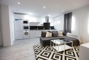 ein Wohnzimmer mit einem Sofa und einer Küche in der Unterkunft Brand new charming apartment next to the river in Sevilla