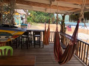 two hammocks hanging from a deck with a table and chairs at Beach Shack Chalet - Garden View Aframe Big Unit in Tioman Island
