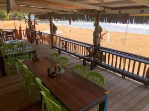 a wooden deck with chairs and tables and a beach at Beach Shack Chalet - Garden View Aframe Big Unit in Tioman Island