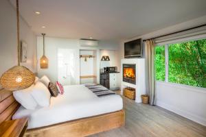 a bedroom with a white bed and a fireplace at Blue Sands Inn, A Kirkwood Collection Hotel in Santa Barbara