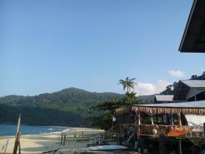 a beach with a building and a palm tree and the ocean at Beach Shack Chalet - Garden View Aframe Big Unit in Tioman Island