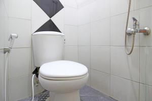 La salle de bains est pourvue de toilettes avec un triangle noir et blanc sur le mur. dans l'établissement RedDoorz near Terminal Condong Catur, à Yogyakarta
