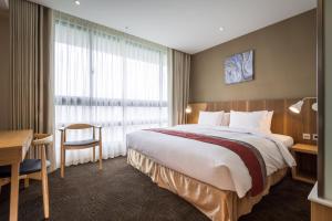 台北的住宿－洛碁大飯店南港館，酒店客房设有一张大床和一张书桌。