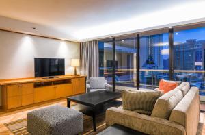 a living room filled with furniture and a tv at Chatrium Residence Sathon Bangkok in Bangkok