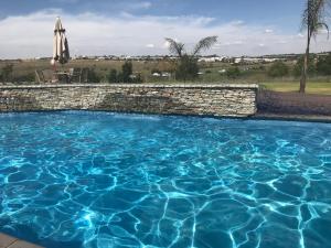 a swimming pool with a stone wall and an umbrella at Regal Inn Hotel Midrand in Midrand