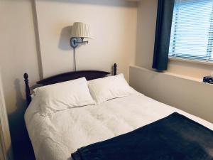 ein Schlafzimmer mit einem Bett mit weißer Bettwäsche und einer Lampe in der Unterkunft Sunshine Coast Suites in Sechelt