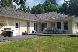 a house with a patio with chairs and a grill at Poolvilla i Höllviken in Höllviken