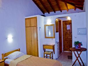 1 dormitorio con cama, mesa y espejo en Villa Kavourakia en Kolios