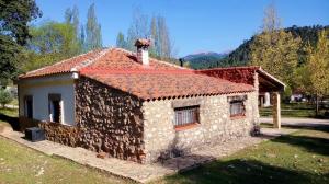 a small stone house with a red roof at Casa Rural en Aldea Cueva Ahumada in Villaverde de Guadalimar