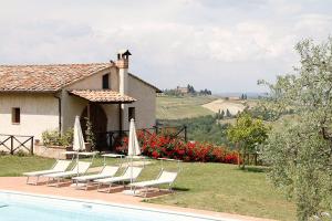 um grupo de cadeiras e guarda-sóis ao lado de uma casa em Le Fonti Di Santa Lucia em San Gimignano