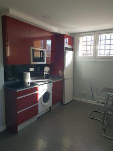 a kitchen with red cabinets and a washing machine at WindRose 0 in Madrid