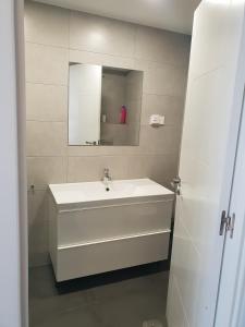 La salle de bains est pourvue d'un lavabo blanc et d'un miroir. dans l'établissement WindRose 0, à Madrid