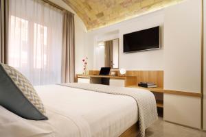 Schlafzimmer mit einem Bett, einem Schreibtisch und einem TV in der Unterkunft Magica Luna Boutique Hotel - Roma in Rom