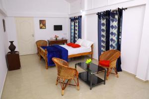 a bedroom with a bed and chairs and a table at Marari PeterLand in Alleppey