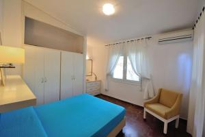 una camera con un letto blu e una sedia di Villa Ftelia a Città di Skiathos