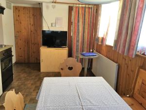 ein Esszimmer mit einem Tisch und einem TV sowie eine Küche in der Unterkunft Chalet Waldesruh 3 Zimmerwohnung in Arosa