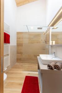 baño con lavabo blanco y alfombra roja en Oberpfaffstallerhof en Collalbo