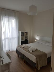 a white bedroom with a large bed and a window at Affittacamere Risorgimento in Lecco