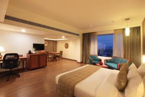 a hotel room with a bed and a desk and chairs at Monsoon Empress Kochi in Cochin