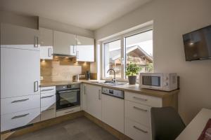 a kitchen with white cabinets and a sink and a window at Appartement de Jager in Söll +5 photos