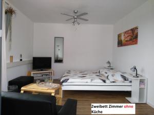 a white bedroom with a bed and a table at Gästehaus Schumann in Essingen