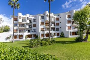 an apartment building with palm trees and a lawn at Apartment Carabela 2 in Alcudia
