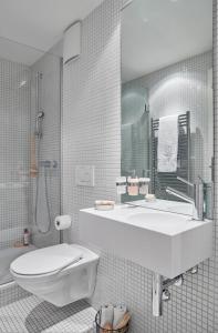 a white bathroom with a sink and a toilet at VISIONAPARTMENTS Binzmühlestrasse 50 - contactless check-in in Zurich