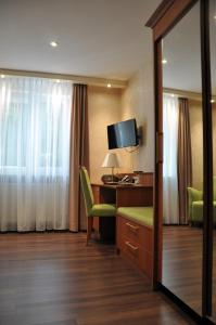 ein Hotelzimmer mit einem Schreibtisch, einem Stuhl und einem Spiegel in der Unterkunft Hotel Anna in Badenweiler