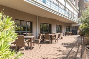 d'une terrasse avec des tables, des chaises et des fenêtres. dans l'établissement Résidence Pierre & Vacances Premium Julia Augusta, à Roquebrune-Cap-Martin