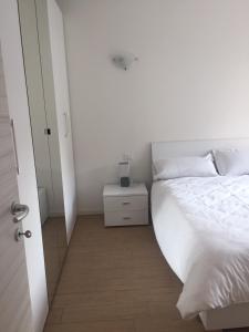 a white bedroom with a bed and a night stand at Residenza Redipuglia in Bussolengo