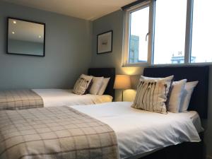 two beds in a room with two windows at The Central Guesthouse in Kelso