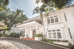 una casa blanca con palmeras delante en Capital O 332 Residence G17 Kemang, en Yakarta