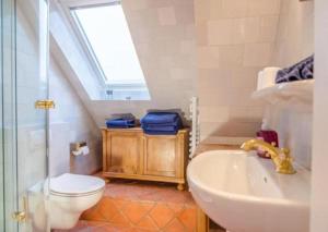 Un baño con lavabo, inodoro y ventana. en Haus Seelord Whg. Smutje, en Braderup 3 fotos más