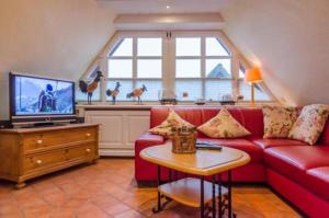 Una sala de estar con un sofá rojo y un televisor. en Haus Seelord Whg. Smutje, en Braderup