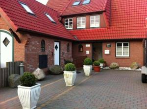 a brick house with a red roof with white planters at Haus Seelord Whg. Smutje in Braderup