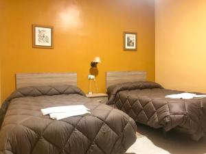2 camas en una habitación con paredes amarillas en El Quijote, en El Toboso