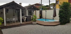 a wooden deck with a swimming pool and a house at Casa para temporada in Florianópolis