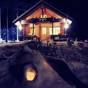 una cabaña de madera en la nieve por la noche en Tarinatupa Simojärvi, en Impiö