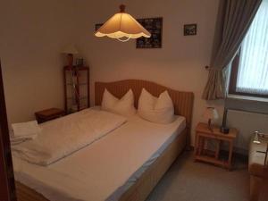ein Schlafzimmer mit einem Bett mit weißer Bettwäsche und einer Lampe in der Unterkunft Apartment Westerheide in Braderup