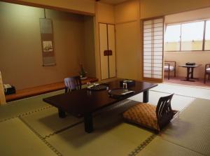 a living room with a table and a chair at Hitomaru Kadan in Akashi