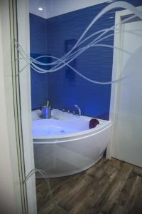 VILLA ADELAIDE SUITE & ROOM في توري آه ماري: حوض استحمام أبيض في حمام بجدران زرقاء