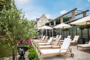 a patio area with chairs, tables and umbrellas at Schlosshotel Münchhausen in Aerzen