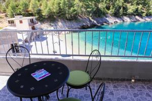 a table and chairs on a balcony with a view of the water at Robinson Bella in Bogomolje