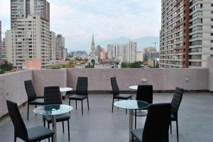 a balcony with tables and chairs and a view of a city at Origen Apart-Hotel in Santiago