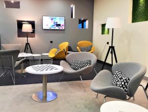 una sala de espera con sillas, mesas y TV en Ibis Styles Vilnius en Vilna
