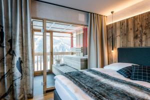 een slaapkamer met een bed en een groot raam bij Die Alm 1350 in Saalbach Hinterglemm