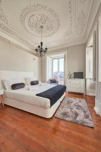 biała sypialnia z dużym łóżkiem i żyrandolem w obiekcie Casa Portuguesa Combro w Lizbonie