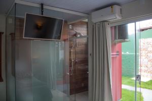 Cette chambre dispose d'une télévision au-dessus d'un mur en verre. dans l'établissement Pousada Estrelas no Mar Florianópolis, à Florianópolis