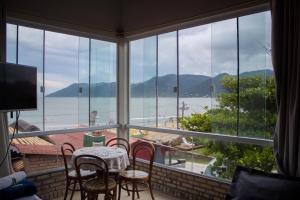 a room with a table and chairs and a large window at Pousada Estrelas no Mar Florianópolis in Florianópolis