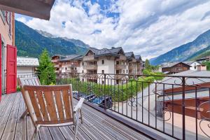 une terrasse en bois avec une chaise sur un balcon avec des bâtiments dans l'établissement Marie Paradis Studio Apt 15, à Chamonix-Mont-Blanc